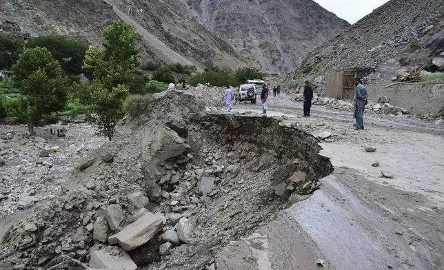 Local residents walk on a damaged road following a cloudburst triggered landslide and flash flood on a highway near the Chilas district, northern Pakistan, Wednesday, July 23, 2025. (AP Photo/Saqib Manzoor)