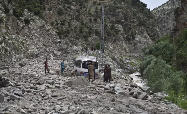 People clear the rubble to recover a vehicle following a cloudburst triggered landslide and flash flood on a highway near the Chilas district, northern Pakistan, Wednesday, July 23, 2025. (AP Photo/Saqib Manzoor)