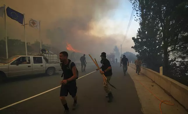 Residents try to extinguish the blazes in Omodos village, Cyprus, during a massive wildfire on the southern side of the east Mediterranean island nation's Troodos mountain range, Thursday, July 24, 2025. (AP Photo/Petros Karadjias)