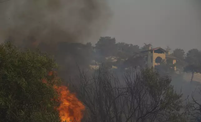 Flames burn near a house in Souni village, Cyprus, during a massive wildfire on the southern side of the east Mediterranean island nation's Troodos mountain range, Thursday, July 24, 2025. (AP Photo/Petros Karadjias)