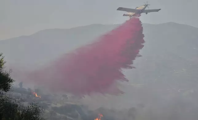 A British aircraft drops retardant liquid on the blazes in Omodos village, Cyprus, during a massive wildfire on the southern side of the east Mediterranean island nation's Troodos mountain range, Thursday, July 24, 2025. (AP Photo/Petros Karadjias)