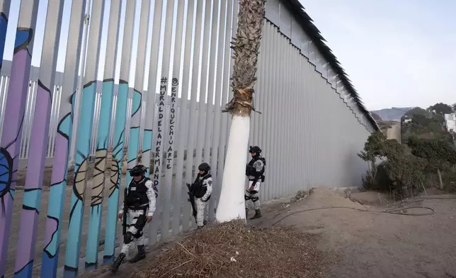 FILE - Members of the Mexican National Guard patrol along the border wall separating Mexico and the United States, in Tijuana, Jan. 20, 2025. (AP Photo/Gregory Bull, File)