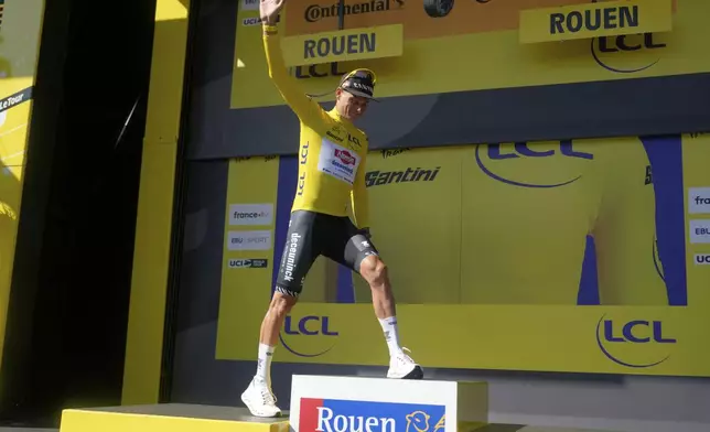 Netherlands' Mathieu van der Poel wearing the overall leader's yellow jersey celebrates on the podium after the fourth stage of the Tour de France cycling race over 172.2 kilometers (107 miles) with start in Amiens and finish in Rouen, France, Tuesday, July 8, 2025. (AP Photo/Mosa'ab Elshamy))