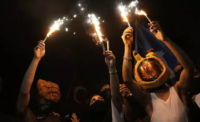 People light flares during a protest called by the main opposition Republican People's Party or (CHP), outside the City Hall in Istanbul, Turkey, Tuesday, July 1, 2025. (AP Photo/Khalil Hamra)
