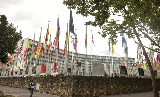 A woman walks by the UNESCO headquarters Tuesday, July 22, 2025 in Paris. (AP Photo/Thomas Padilla)