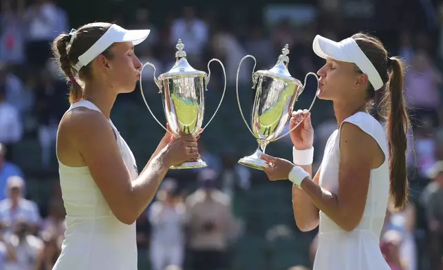 Veronika Kudermetova of Russia,right, and Elise Mertens of Belgium celebrate with the trophies after winning against Jelena Ostapenko of Latvia and Su-Weih Hsieh of Taiwan their women's doubles final match at the Wimbledon Tennis Championships in London, Sunday, July 13, 2025.(AP Photo/Kirsty Wigglesworth)