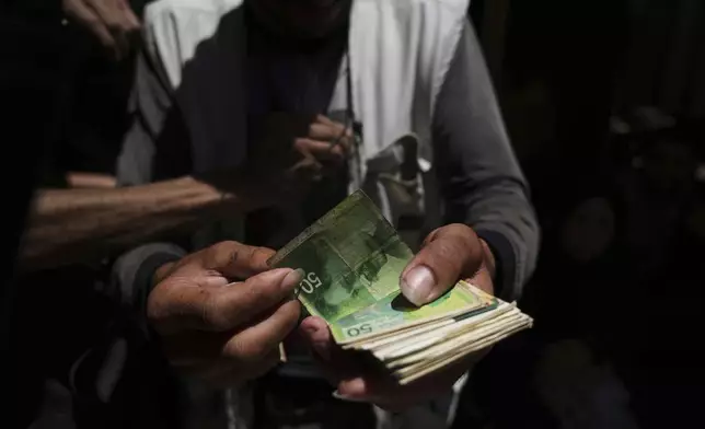 A Palestinian vegetable merchant shows worn-out Israeli currency Wednesday, July 9, 2025, in Gaza City. (AP Photo/Jehad Alshrafi)
