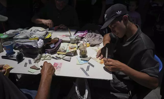 Palestinians repair worn-out Israeli currency Wednesday, July 9, 2025, in Gaza City. (AP Photo/Jehad Alshrafi)