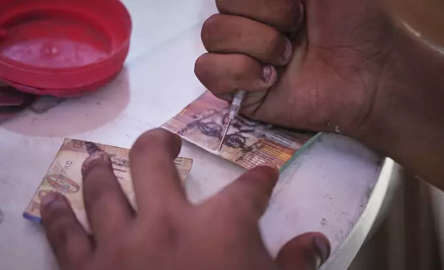A Palestinian man repairs worn-out Israeli currency Wednesday, July 9, 2025, in Gaza City. (AP Photo/Jehad Alshrafi)
