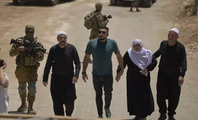 Syrian Druze people cross back into Syria as they walk at the Israeli-Syrian border, in the Israeli-controlled Golan Heights town of Majdal Shams, Thursday, July 17, 2025. (AP Photo/Leo Correa)