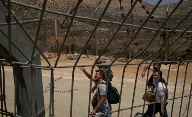 Syrian Druze people cross back into Syria as they walk at the Israeli-Syrian border, in the Israeli-controlled Golan Heights town of Majdal Shams, Thursday, July 17, 2025. (AP Photo/Leo Correa)