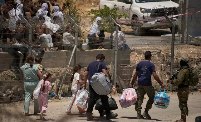 A Syrian Druze family cross back into Syria as they walk on the Israeli-Syrian border, at the Israeli-controlled Golan Heights town of Majdal Shams, Thursday, July 17, 2025. (AP Photo/Leo Correa)