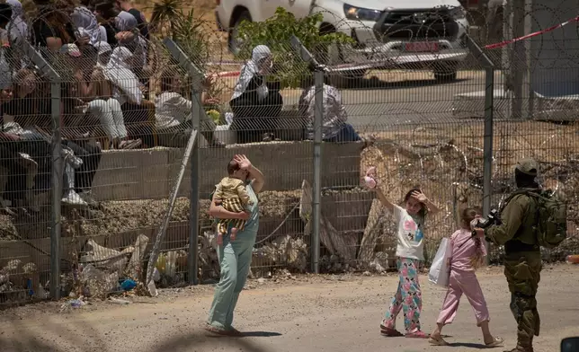 Members of a Syrian Druze family wave goodbye as they cross back into Syria at the Israeli-Syrian border, in the Israeli-controlled Golan Heights town of Majdal Shams, Thursday, July 17, 2025. (AP Photo/Leo Correa)