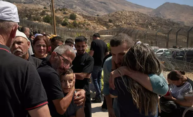 Druze from Syria hug relatives from Israeli Druze community before crossing the Israeli-Syrian border, in the town of Majdal Shams, in the Israeli-controlled Golan Heights, Thursday, July 17, 2025. (AP Photo/Leo Correa)