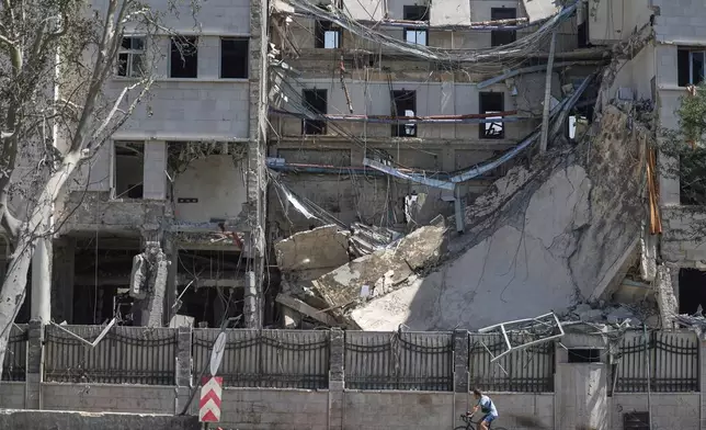 A man rides his bicycle passes in front the Syrian Defense Ministry building which on Wednesday was heavily damagedby Israeli airstrikes in Damascus, Syria, Thursday, July 17, 2025. (AP Photo/Ghaith Alsayed)