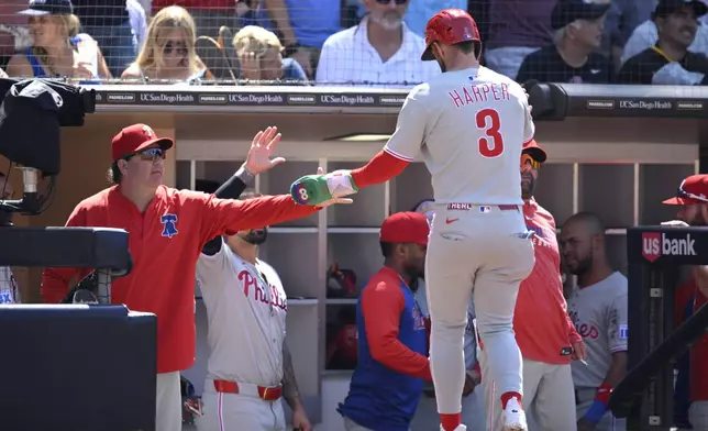 Philadelphia Phillies' Bryce Harper (3) is greeted at the dugout after scoring on a double hit by J.T. Realmuto during the eighth inning of a baseball game against the San Diego Padres, Sunday, July 13, 2025, in San Diego. (AP Photo/Orlando Ramirez)