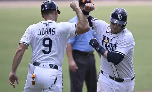Tampa Bay Rays' Danny Jansen, right, celebrates his solo home run with third base coach Michael Johns (9) while rounding the bases during the fourth inning of a baseball game against the Baltimore Orioles, Sunday, July 20, 2025, in Tampa, Fla. (AP Photo/Phelan M. Ebenhack)