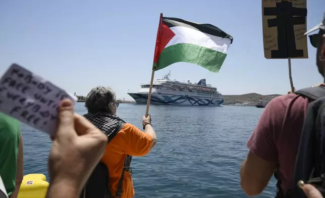 A protester waves a Palestinian flag as people demonstrates in front of a cruise ship carrying Israeli tourists and trying to approach the Aegean Sea island of Syros, Greece, Tuesday, July 22, 2025. (Nikos Panagiotopoulos/InTime News via AP)