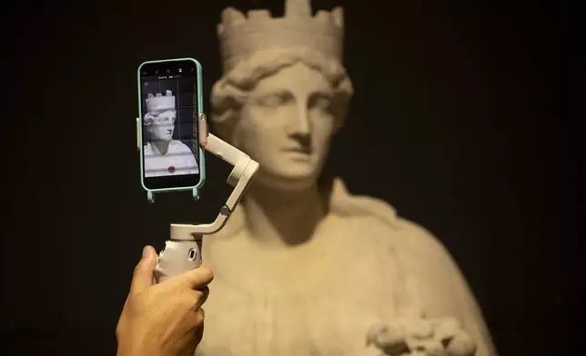 A journalist films a sculpture during a press tour at the National Museum in Rio de Janeiro, ahead of its temporary reopening to the public following a 2018 fire, Monday, June 30, 2025. (AP Photo/Bruna Prado)