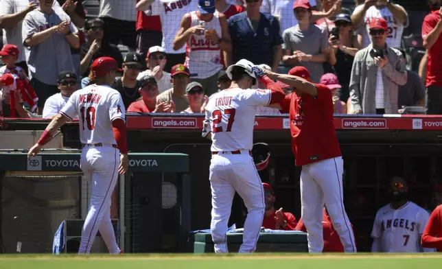 Los Angeles Angels' Mike Trout, center, is greeted by teammates after hitting a home run during the fifth inning of a baseball game against the Seattle Mariners, Sunday, July 27, 2025, in Anaheim, Calif. (AP Photo/William Liang)