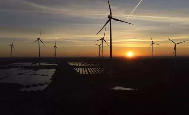 FILE - Wind turbines operate as the sun rises at the Klettwitz Nord solar energy park near Klettwitz, Germany, Oct. 16, 2024. (AP Photo/Matthias Schrader, File)