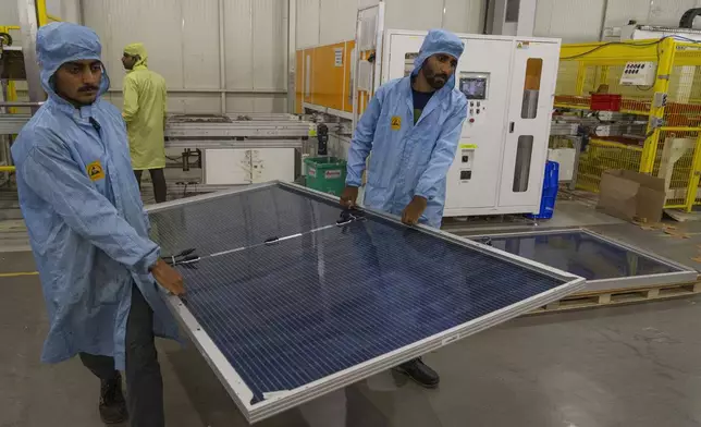 FILE - Employees carry solar panels at the Adani New Industries Limited in the port town of Mundra in Western India's Gujarat state, India, Sept. 20, 2023. (AP Photo/Rafiq Maqbool, File)