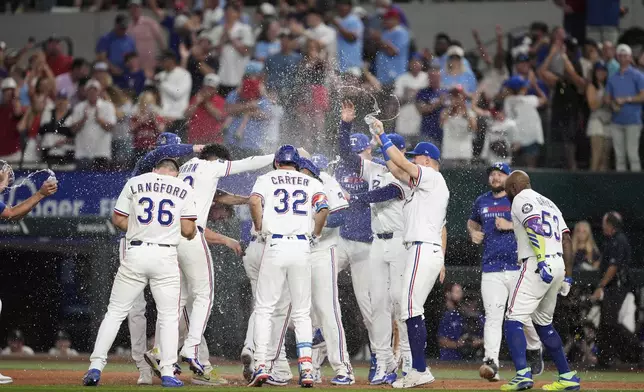 The Texas Rangers celebrate after a run-scoring single by Marcus Semien in the 10th inning of a baseball game against the Atlanta Braves, Saturday, July 26, 2025, in Arlington, Texas. (AP Photo/Tony Gutierrez)