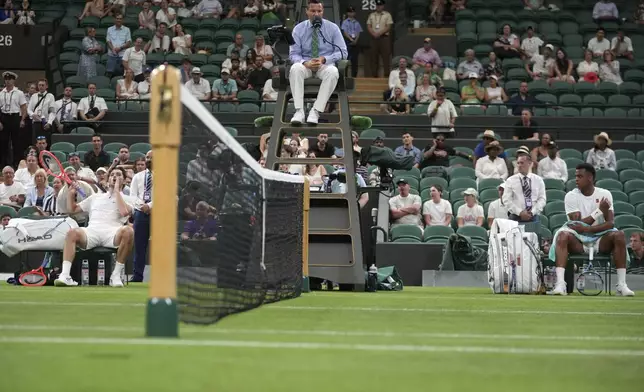 Taylor Fritz of the U.S. and Giovanni Mpetshi Perricard of France, right sit on their bench after the first round men's single match was suspended at the Wimbledon Tennis Championships in London, Monday, June 30, 2025. (AP Photo/Kin Cheung)