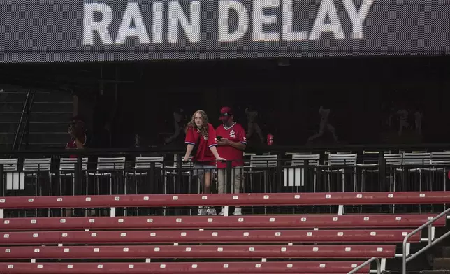 Fans wait out a rain delay during the fifth inning of a baseball game between the St. Louis Cardinals and the Atlanta Braves Sunday, July 13, 2025, in St. Louis. (AP Photo/Jeff Roberson)