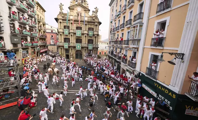Revelers run with bulls from Fuente Ymbro ranch during the first day of the running of the bulls at the San Fermín fiestas in Pamplona, Spain, Monday, July 7, 2025. (AP Photo/Miguel Oses)