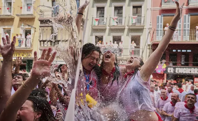 Revellers cool off with water thrown from balconies during the start of nine days of uninterrupted partying in Pamplona's famed running-of-the-bulls festival in Pamplona, Spain, Sunday, July 6, 2025. (AP Photo/Miguel Oses)