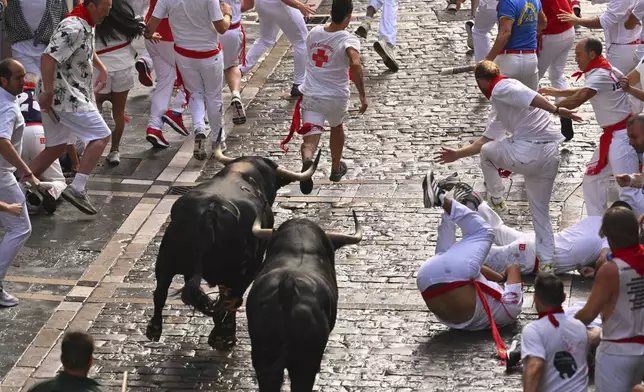 Revelers run with bulls from Fuente Ymbro ranch during the first day of the running of the bulls at the San FermÌn fiestas in Pamplona, Spain, Monday, July 7, 2025. (AP Photo/Miguel Oses)