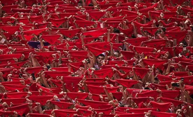 Revelers hold up red neckties as they pack the main square during the start of nine days of uninterrupted partying in Pamplona's famed running-of-the-bulls festival in Pamplona, Spain, Sunday, July 6, 2025. (AP Photo/Miguel Oses)