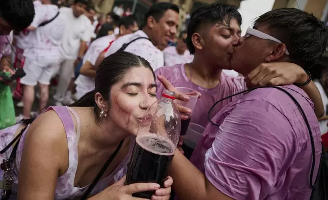 Revelers drink from leather wine sacks as they pack the main square during the official start of nine days of uninterrupted partying in Pamplona's famed running-of-the-bulls festival in Pamplona, Spain, Sunday, July 6, 2025. (AP Photo/Miguel Oses)