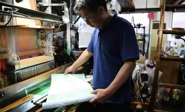 Hironori Fukuoka, the fourth-generation successor to his Nishijinori business, looks at the fabric that is a collaboration with AI in Kyoto, western Japan on July 3, 2025. (AP Photo/Yuri Kageyama)