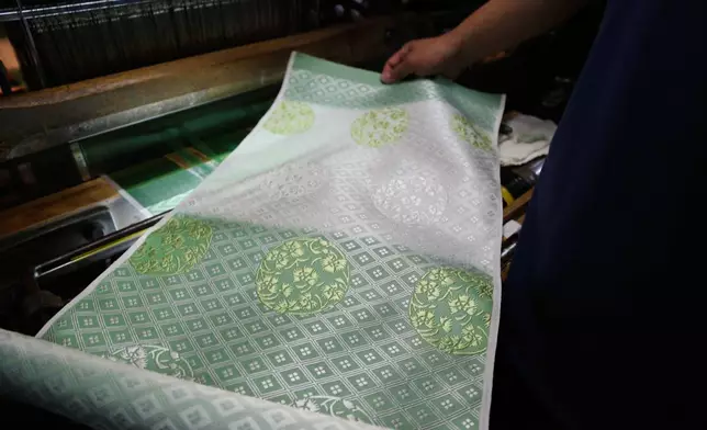 Hironori Fukuoka, the fourth-generation successor to his Nishijinori business, looks at the fabric that is a collaboration with AI in Kyoto, western Japan on July 3, 2025. (AP Photo/Yuri Kageyama)