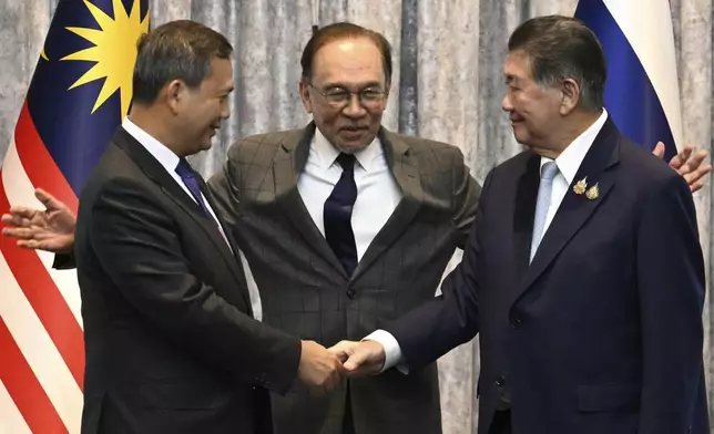 Cambodia's Prime Minister Hun Manet, left and Thailand's acting Prime Minister Phumtham Wechayachai, right shake hands as Malaysia's Prime Minister Anwar Ibrahim gestures after talks on a possible ceasefire between Thailand and Cambodia in Putrajaya, Malaysia, Monday, July 28, 2025. (Mohd Rasfan/Pool Photo via AP)