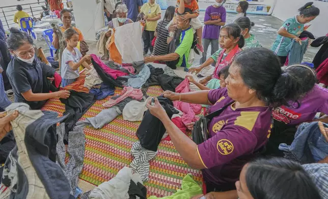 Thai residents select donated clothes as they fled homes following the clashes between Thai and Cambodian soldiers, at an evacuation center in Surin province, Thailand, Monday, July 28, 2025. (AP Photo/Sakchai Lalit)