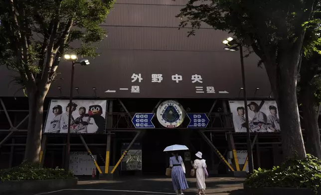 Visitors walk past the Jingu stadium in Tokyo, Monday, June 30, 2025. (AP Photo/Louise Delmotte)