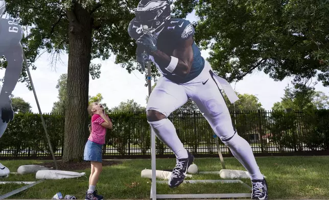 A young girl looks up and reacts to a cut out of Philadelphia Eagles' A.J. Brown at the team's NFL football training camp, Saturday, July 26, 2025. (AP Photo/Chris Szagola)