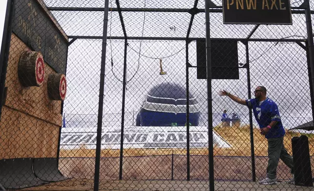A fan throws an axe in a cage during the Seattle Seahawks NFL football team's training camp Friday, July 25, 2025, in Renton, Wash. (AP Photo/Lindsey Wasson)