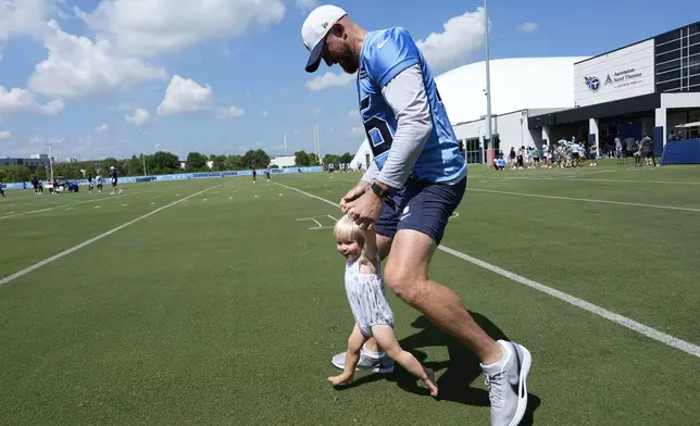 Tennessee Titans long snapper Morgan Cox, right, spends time with his son Thomas after practice at the team's NFL football training camp Wednesday, July 23, 2025, in Nashville, Tenn. (AP Photo/George Walker IV)