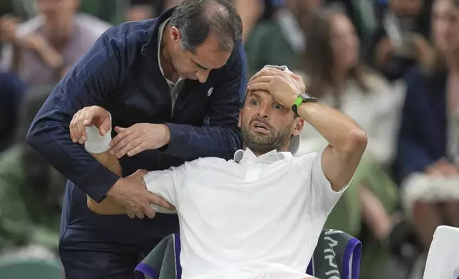 Bulgaria's Grigor Dimitrov gets treatment after he went down with an injury which forced him to retire injured from a fourth round men's singles match against Italy's Jannik Sinner at the Wimbledon Tennis Championships in London, Monday, July 7, 2025. (AP Photo/Kin Cheung)