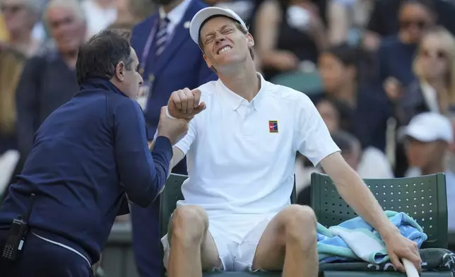 Italy's Jannik Sinner grimaces as he receives medical treatment against Bulgaria's Grigor Dimitrov during a fourth round men's singles match at the Wimbledon Tennis Championships in London, Monday, July 7, 2025. (AP Photo/Kin Cheung)