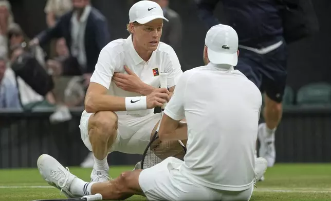 Italy's Jannik Sinner checks on Bulgaria's Grigor Dimitrov after he went down with an injury during a fourth round men's singles match at the Wimbledon Tennis Championships in London, Monday, July 7, 2025. (AP Photo/Kin Cheung)
