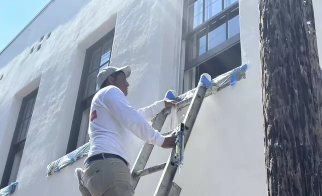 Luis Hernandez paints a second-floor window on a home in Savannah, Ga., Tuesday, July 29, 2025, as people across the southeastern U.S. dealt with extreme summer heat. (AP Photo/Russ Bynum)
