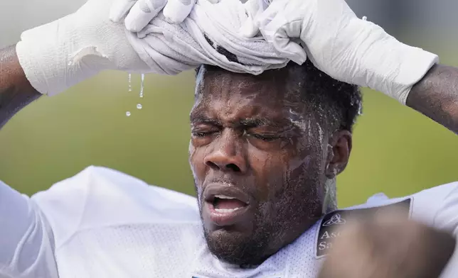 Tennessee Titans linebacker Arden Key uses a wet towel to cool off after practice at the team's NFL football training camp Tuesday, July 29, 2025, in Nashville, Tenn. (AP Photo/George Walker IV)