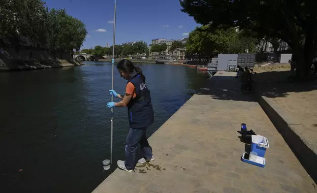 Emilie Vilana of Fluidion takes a sample from the Seine river to test the water quality, Thursday, July 3, 2025 for the opening of the three Seine swimming pools during the 'Paris Plages' event from July 5 to Aug. 31 in Paris. (AP Photo/Aurelien Morissard)