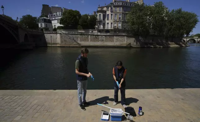 Mathias Hajeut, left, and Emilie Vilana of Fluidion test the Seine river water quality, Thursday, July 3, 2025 for the opening of the three Seine swimming pools during the 'Paris Plages' event from July 5 to Aug. 31 in Paris. (AP Photo/Aurelien Morissard)