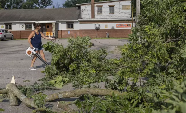 Dawn Sands cleans the parking lot at Robin's Nest Bar &amp; Grill after a storm with extreme winds in La Crosse, Wis., Tuesday, July 29, 2025. (Saskia Hatvany/La Crosse Tribune via AP)